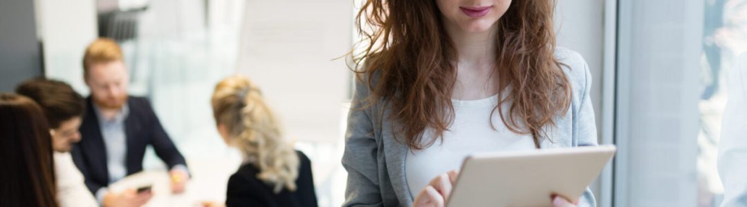 Elegant smart businesswoman in company office holding tablet and smiling